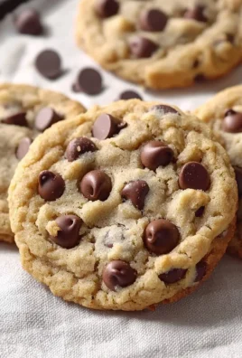Crumbl chocolate chip cookies stacked on a plate, fresh from the oven.