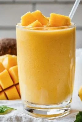Creamy Mango Coconut Milk Smoothie in a glass with tropical fruits