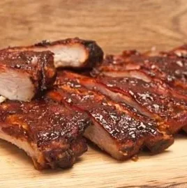 Oven-cooked baby back ribs served with BBQ sauce and sides.
