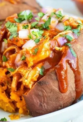 BBQ chicken stuffed sweet potatoes topped with fresh herbs and spices.