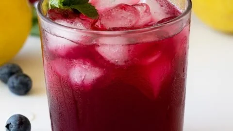 A refreshing glass of blueberry lemonade with fresh blueberries and lemon slices.