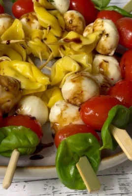 Caprese skewers with tortellini, cherry tomatoes, basil, and mozzarella on a platter