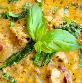 Bowl of creamy Tuscan chicken soup with vegetables and herbs