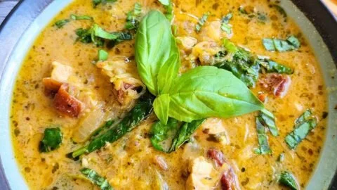 Bowl of creamy Tuscan chicken soup with vegetables and herbs