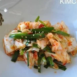 Homemade Green Cabbage Kimchi in a glass jar, showcasing vibrant colors and textures.