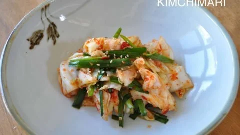 Homemade Green Cabbage Kimchi in a glass jar, showcasing vibrant colors and textures.