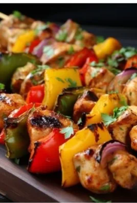 Oven-baked chicken kabobs served on a platter with colorful veggies.