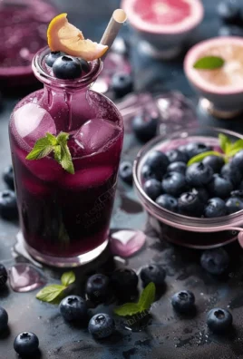 Homemade blueberry soda served in a glass with fresh blueberries and ice.
