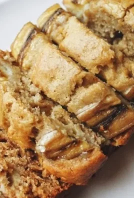 Loaf of classic banana bread topped with slices of ripe bananas