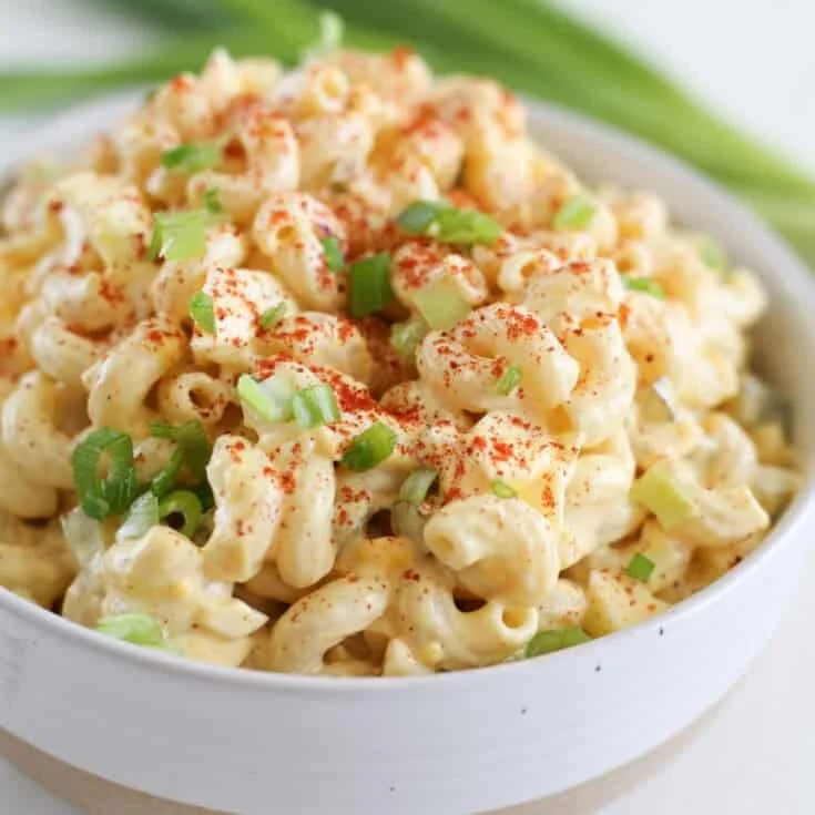 A bowl of Deviled Egg Pasta Salad garnished with herbs and eggs.