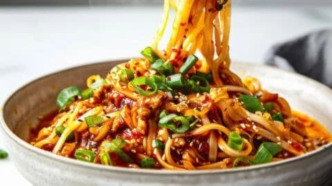Delicious plate of Easy Szechuan Noodles (Dan Dan Noodles) garnished with herbs