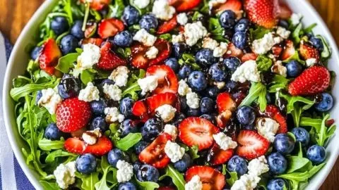 Fresh arugula salad topped with colorful berries and a light vinaigrette.