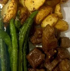 Garlic balsamic steak bites served on a plate with herbs