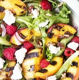 Grilled peach salad topped with fresh greens and maple vinaigrette dressing.