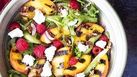 Grilled peach salad topped with fresh greens and maple vinaigrette dressing.
