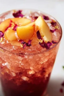 Refreshing Hibiscus Peach Iced Tea in a glass with peach slices and hibiscus flowers