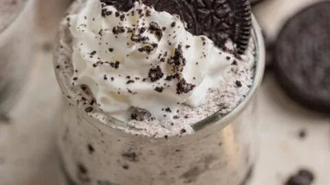 Oreo no-bake cheesecake cups topped with crushed Oreos and whipped cream