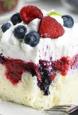 Delicious Summer Berry Poke Cake topped with fresh mixed berries and cream.