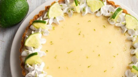 No-bake Vegan Key Lime Pie topped with lime slices and coconut cream.