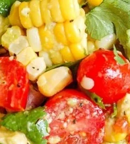 Bowl of colorful avocado corn salad with fresh vegetables and herbs