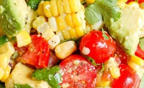 Bowl of colorful avocado corn salad with fresh vegetables and herbs