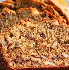 Homemade banana nut bread with walnuts and sliced bananas on a wooden table