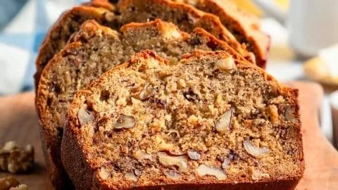 Homemade banana nut bread with walnuts and sliced bananas on a wooden table