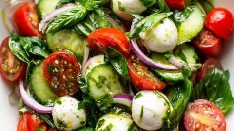 Fresh basil salad with colorful vegetables and a drizzle of dressing
