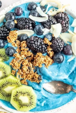 Delicious blue smoothie bowl topped with fruits and seeds