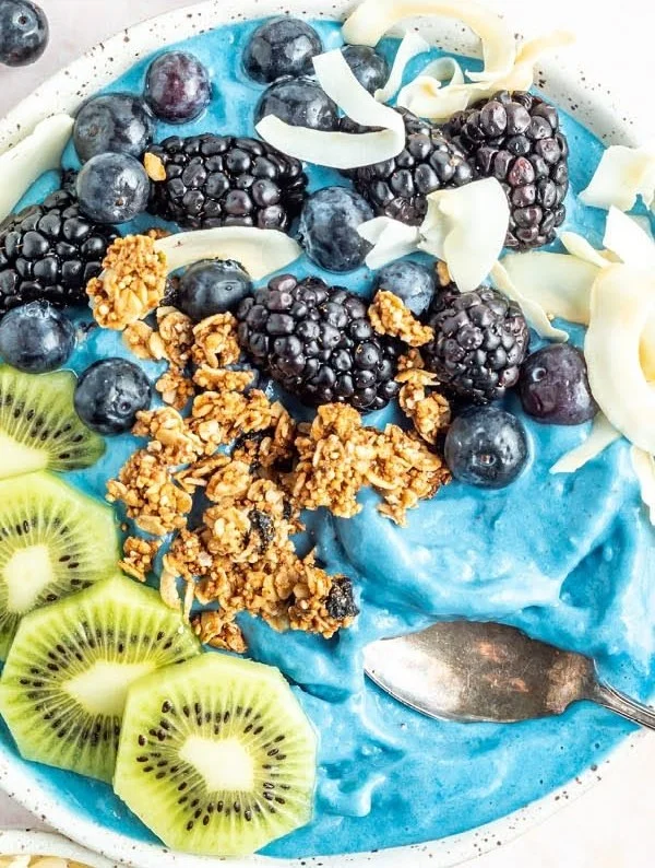 Delicious blue smoothie bowl topped with fruits and seeds