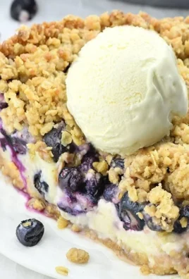 Delicious blueberry crumble cheesecake pie topped with juicy blueberries and crunchy crumble.