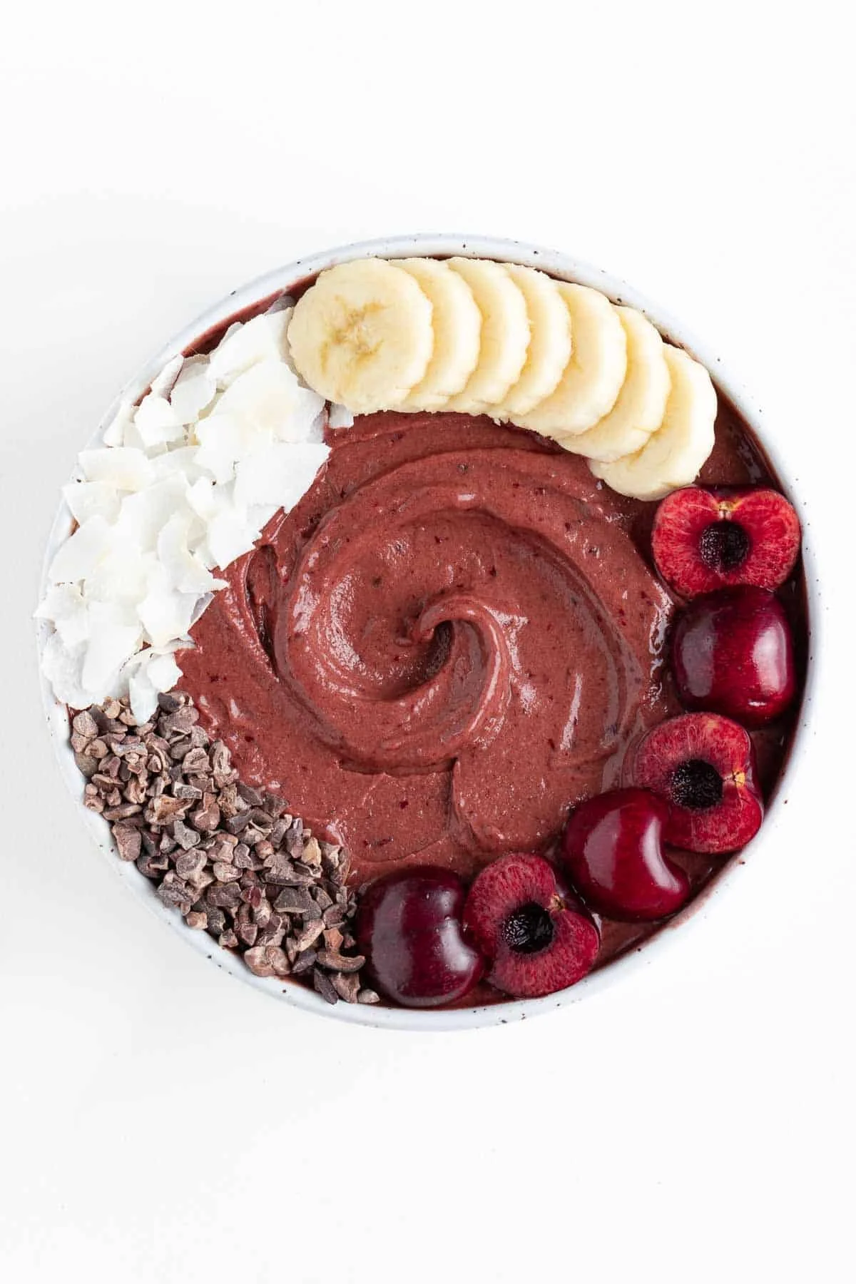 Chocolate cherry smoothie bowl topped with fresh cherries and chocolate chips