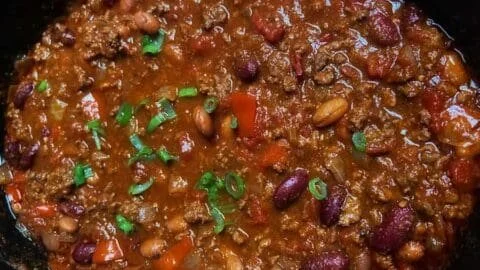Bowl of classic slow cooker chili with toppings and herbs