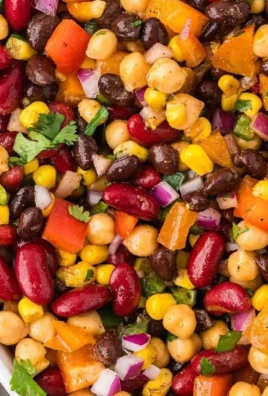 A colorful cold bean salad featuring various beans and fresh vegetables.
