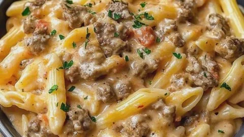 Creamy beef pasta dish garnished with herbs in a bowl