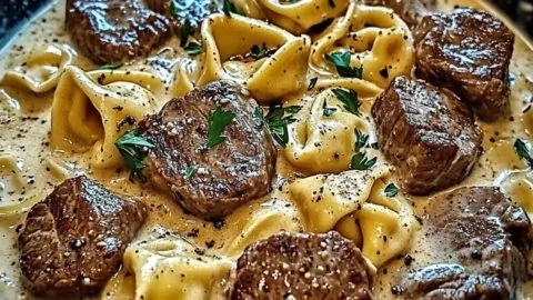 Creamy garlic steak tortellini skillet dish topped with herbs in a pan