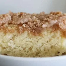 Slice of easy classic coffee cake on a plate with a cup of coffee.