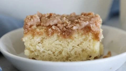Slice of easy classic coffee cake on a plate with a cup of coffee.