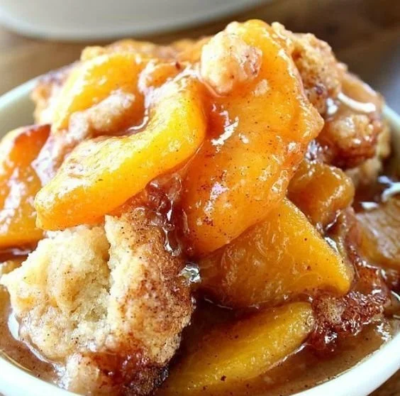 Delicious fresh peach cobbler served warm with vanilla ice cream.