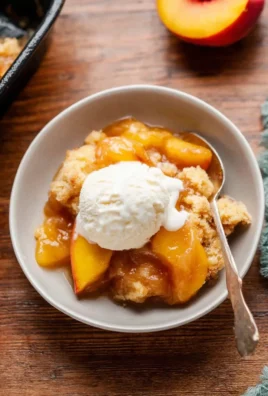 Delicious homemade fresh peach cobbler served warm with a scoop of ice cream