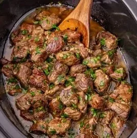 Delicious Garlic Butter Steak Bites cooked in a slow cooker, garnished with herbs.