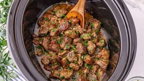 Delicious Garlic Butter Steak Bites cooked in a slow cooker, garnished with herbs.