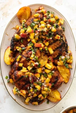 Grilled Jalapeño Peach Chicken on a plate with fresh herbs and peach slices