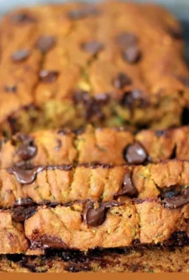 Slice of healthy homemade pumpkin zucchini bread on a wooden cutting board.