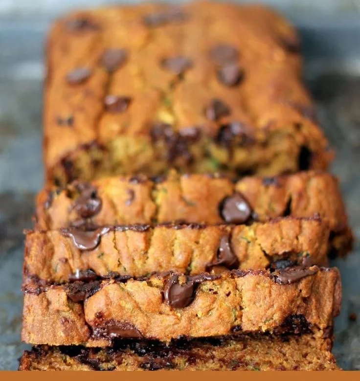Slice of healthy homemade pumpkin zucchini bread on a wooden cutting board.