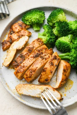 Juicy baked chicken breast served with fresh vegetables on a plate.