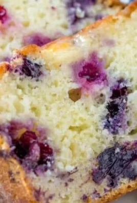 Slice of moist Lemon Blueberry Bread with fresh blueberries and lemon zest