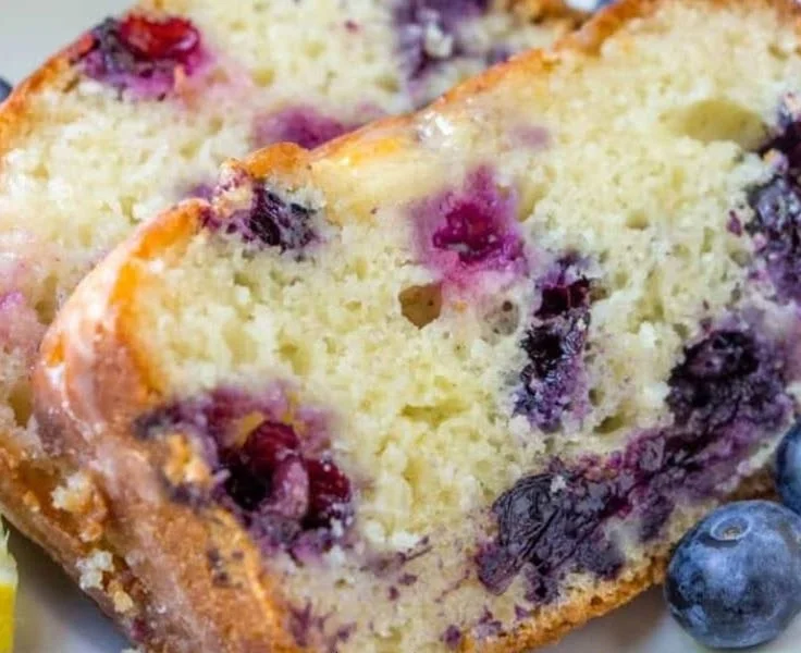 Slice of moist Lemon Blueberry Bread with fresh blueberries and lemon zest