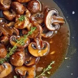 Pan-seared mushrooms with caramelized shallots and thyme served in a dish.