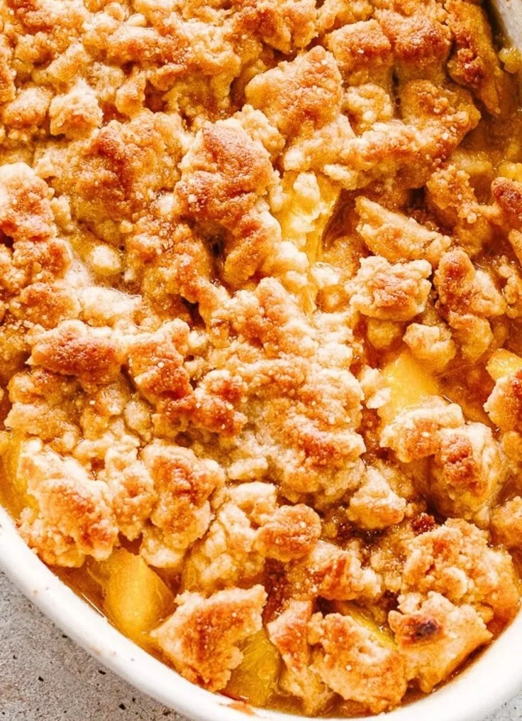 Delicious homemade peach cobbler served warm with ice cream.